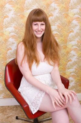 Chloé, rousse entièrement naturelle, se déshabille sur une chaise.